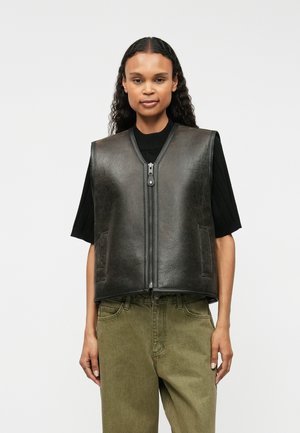 Zwarte leren vest met een rits aan de voorkant, ronde halslijn en twee zijzakken, gecombineerd met een olijfgroene onderkant. Soepele textuur, minimalistisch ontwerp.