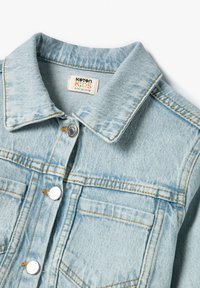 Chaqueta de denim para niño de color azul claro con cuello puntiagudo, botones a presión plateados y costuras naranjas. Presenta bolsillos en el pecho y una textura suave.