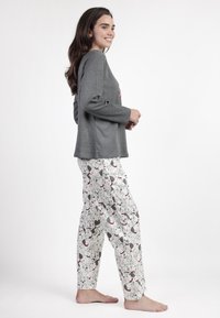 Camiseta de manga larga gris con un gráfico rojo; pantalones blancos con un estampado de perro en negro y gris. Tela suave, ajuste relajado y estilo casual.