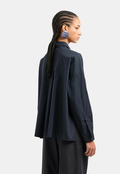 Camicia a maniche lunghe blu navy con vestibilità comoda, dotata di colletto classico, polsini con bottone e una piega sul retro per maggiore volume.