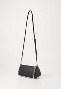 Black faux leather crossbody bag with a curved shape, silver chain accent, and an adjustable strap. Smooth texture with zipper closure.