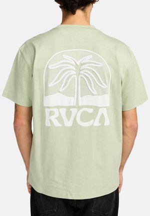 Light green cotton t-shirt featuring a large white palm tree graphic and "RVCA" text on the back. Short sleeves, relaxed fit, smooth texture.