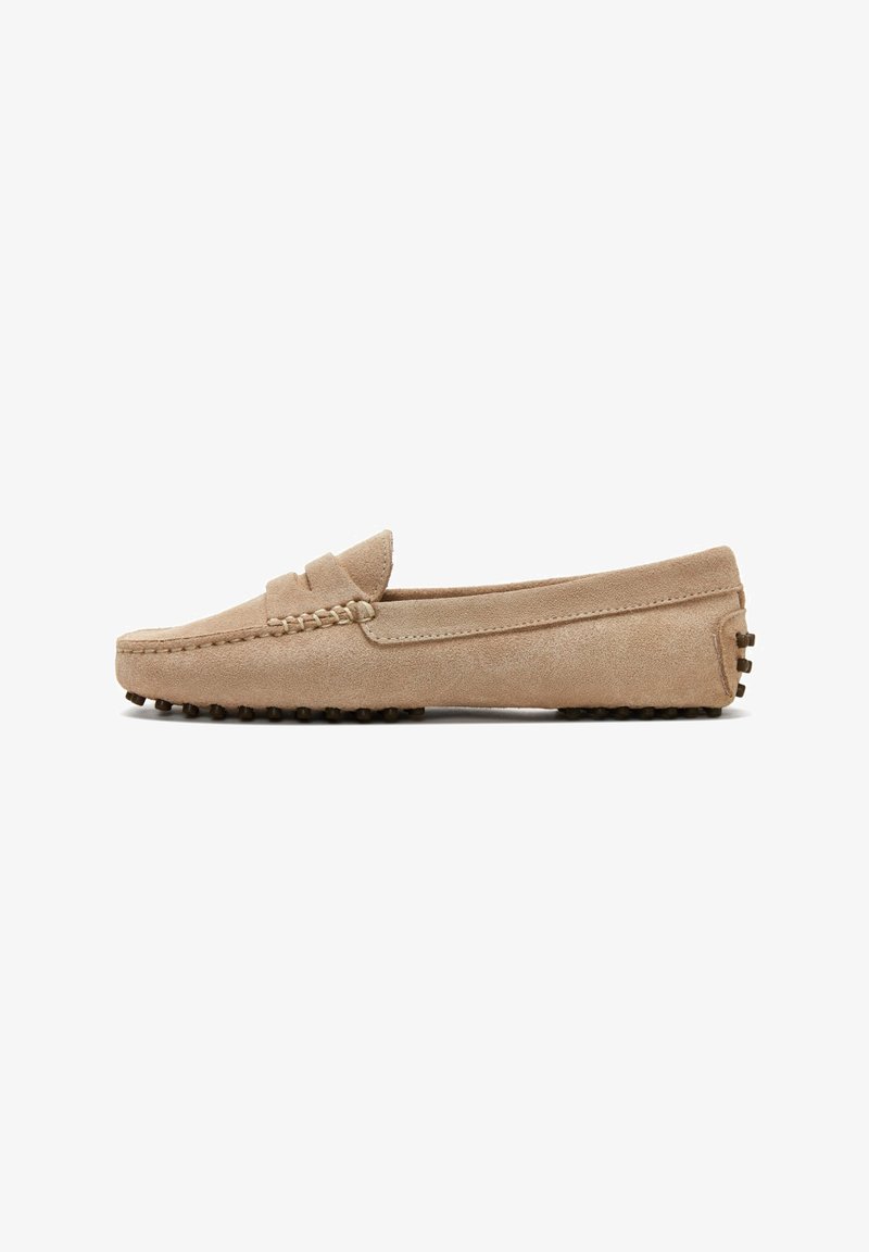 Suede loafers in beige, featuring a moccasin-style design, stitched accents, flat soles with rubber studs, and a slip-on shape.