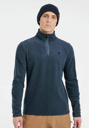 Marineblauwe fleece pullover met een hoge kraag, kwart-rits en logo-detail. Zachte textuur en lange mouwen, gecombineerd met een bijpassende beanie.