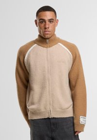 Beige- und Camelfarbener Wollmischung-Zipper-Pullover. Verfügt über gerippte Bündchen und Saum, ein Farbblock-Design mit weißen Akzenten sowie ein Logo-Label am Ärmel.
