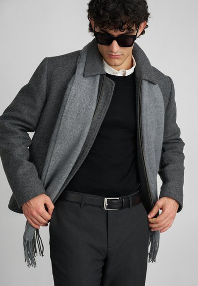 Gray wool jacket with contrasting light gray collar, worn over a black sweater. Featured accessories include a black belt and sunglasses.