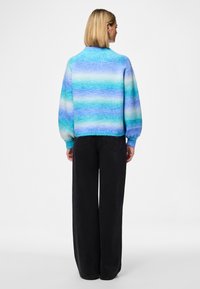 Knitted sweater featuring horizontal stripes in shades of blue and aqua, round neck, and puffed sleeves. Paired with black wide-leg pants.