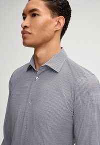 Knöpfenhemd in Marineblau mit einem geometrischen Rautenmuster, versehen mit einem spitzen Kragen und glattem Baumwollstoff, konzipiert für eine taillierte Passform.
