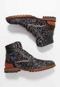 Paire de bottines à motifs noir et blanc avec accents en cuir marron et en suède, cols rembourrés et semelles en caoutchouc robustes.