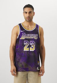 Maglia da basket viola con la scritta "Lakers" e il numero "23" in oro. Motivo a pois e texture a rete con bordature gialle. Logo Nike visibile.