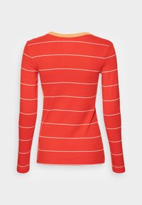 Rød langærmet skjorte med hvide vandrette striber, rund halsudskæring med orange kant, og et tætsiddende design.