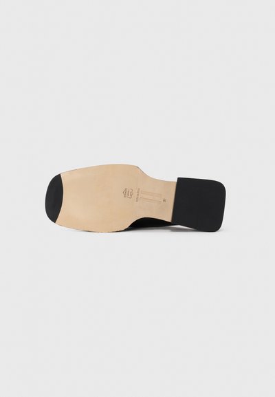 Semelle de chaussure noire à semelle en cuir avec un talon carré, affichant la taille 37 et un tampon "Fabriqué en Espagne".