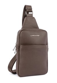 Borsa a tracolla in pelle marrone con superficie testurizzata, dotata di una tasca frontale con zip e tracolla regolabile. Logo "Lancaster" in argento sul davanti.