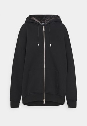 Felpa nera con zip, caratterizzata da un cappuccio foderato, tasca frontale e aperture laterali. Realizzata in un tessuto morbido con una finitura texturizzata. Accessori in metallo argentato.