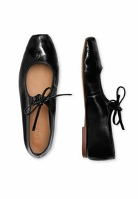 Ballerine in pelle nera con punta rotonda, ritaglio aperto e dettaglio del lacetto. Caratterizzate da una finitura liscia e lucida e suola piatta in legno.