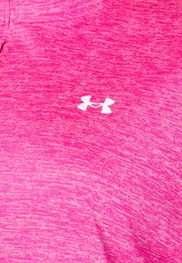 Ružičasta heathered tkanina s središnjim bijelim logotipom Under Armour, koja prikazuje teksturu i detalje šivanja sportske odjeće.