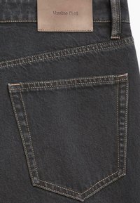 Jean en denim foncé avec une seule poche arrière dotée de surpiqûres orange contrastantes et d'une étiquette en cuir estampillée "Massimo Dutti".