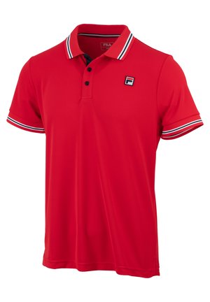 Crvena polo majica od glatkog materijala s ovratnikom i tri dugmeta. Prugasti detalji u mornarsko plavoj i bijeloj boji na rukavima. Grb na prsima.