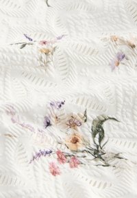 Bílé texturované látky s květinovými vzory v růžové, fialové a zelené barvě. Jemné motivy listů zdůrazňují design a dodávají texturu.