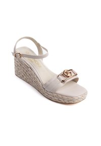 Sandalia de cuña beige con tiras en el tobillo, que presenta un hebilla en tono dorado y suela de yute trenzado. Parte superior de cuero suave con una plantilla plana.