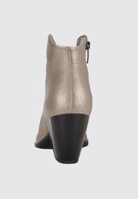 Botte en cuir beige à la cheville avec un talon carré noir et une fermeture éclair sur le côté, vue de dos.