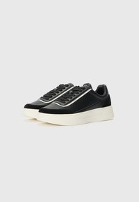 Sorte sneakers med glat læder og ruskindsdetaljer, med en hvid mellemsål og sølvfarvet accentstribe langs siderne, rund tådesign.