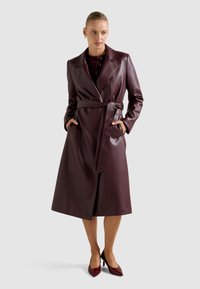 Μπορντό δερμάτινο παλτό τύπου trench με ζώνη, γιακά πέτο, πλαϊνές τσέπες και κομψό, μακρύ μέχρι το γόνατο σχέδιο.