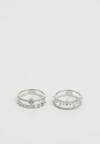 Sett med to sølvringer med intrikate design; den ene med en blomsterdetalj og den andre prydet med flere klare edelsteiner.