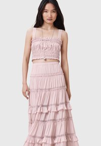 Lyserød to-delt sæt bestående af en smocked crop top og en lagdelt maxi nederdel med flæser og blonde detaljer. Letvægts, luftig stof.