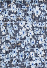 Tejido texturizado con una base azul marino y patrones florales abstractos en azul claro y blanco, salpicados con toques de dorado.