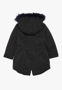 Svart parka med huva i fuskpäls, elastisk midja och långa ärmar. Slätt tyg med matt finish och inga synliga mönster.