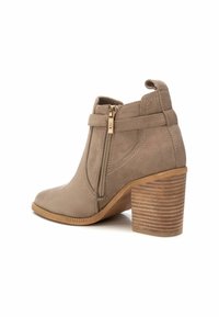 Beżowe zamszowe botki za kostkę z bocznym zamkiem, stacked wooden heel i szytymi detalami na cholewce. Okrągły kształt noska.