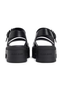 Μαύρα πλατφόρμα σανδάλια με λείο δερμάτινο επάνω μέρος, ανοιχτή πίσω σχεδίαση, ρυθμιζόμενο λουράκι στο αστράγαλο και υφή στη λαστιχένια σόλα. Παρουσιάζει λεπτομέρεια με λογότυπο.