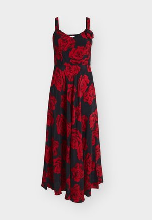 Robe longue noire sans manches avec larges bretelles, motif floral de roses rouges, corsage ajusté et jupe évasée avec une fleur en tissu sur une bretelle.