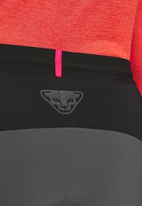 Černé a šedé legíny s přiléhavým střihem, zdobené matným černým zvířecím logem a růžovým akcentem na pásu.