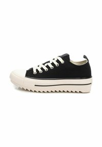 Zapatilla de lona negra con puntera de goma, cordones blancos y una suela blanca a rayas con un patrón de zigzag.