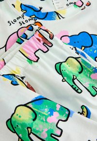 Colorful cotton top featuring playful elephant designs. White background with blue, green, and pink accents. Rounded neckline and pocket detail.