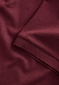 Bordo audinys su lygia tekstūra, turintis įmautą kraštą ir siūles, pagamintas iš minkštos, tamprios medžiagos, tinkamos drabužiams.