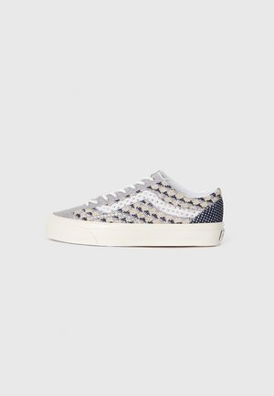 Sneakers with a grey and navy textured fabric, featuring a layered pattern, white laces, and a cream-colored rubber sole.