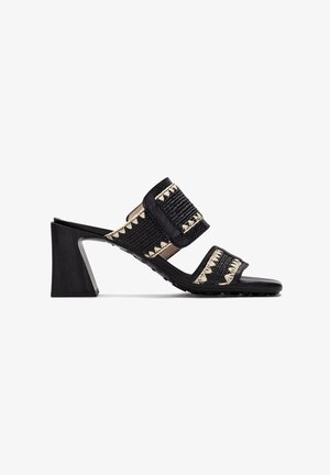 Mule nere con tacco alto, dotate di cinturini in tessuto intrecciato decorati con dettagli crema, con un tacco in legno spesso e una soletta testurizzata.