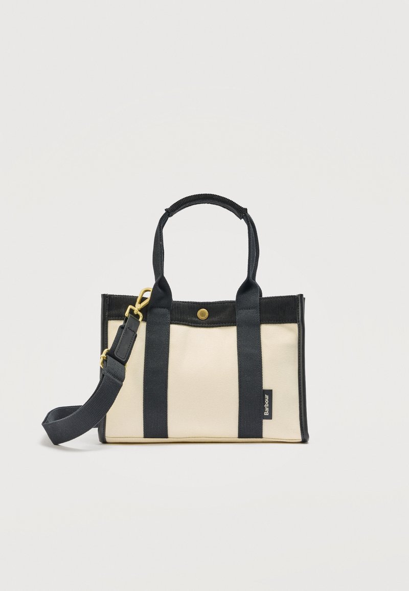 Τσάντα ώμου από καμβά εκρού με μαύρες λαβές, περίγραμμα, αποσπώμενο ιμάντα ώμου και μια μικρή ετικέτα με εμπορικό σήμα στην μπροστινή πλευρά.