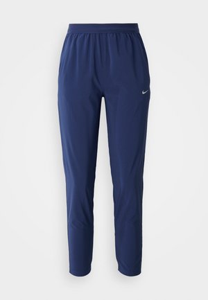 Tummansiniset urheiluhousut, joissa on joustava vyötärö, kapenevat lahkeet, kevyestä kankaasta valmistettu, jonka lantiolla on pieni hopeinen logo.