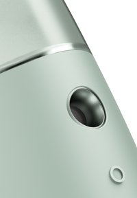 Produit cylindrique vert clair avec une accent en argent, comportant une ouverture circulaire et un intérieur noir texturé, finition extérieure lisse.