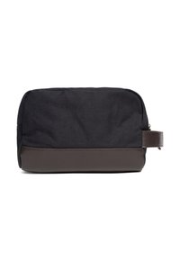 Musta kangasmeikkipussi jossa on ruskea nahkapohja, suorakulmainen muoto, vetoketjusuljin ja sivukahva, joka helpottaa kantamista.