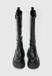 Crne kožne čizme do koljena s glatkom teksturom, s debelim potplatima i petljom na vrhu za lako oblačenje.