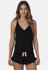 Ensemble de pyjama noir comprenant un haut à bretelles fines avec un décolleté en V et un short noir avec un accent en nœud rose et des bords volantés.
