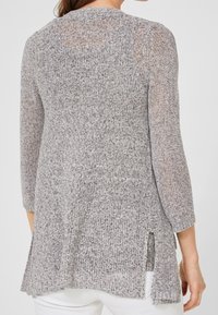 Grå stickad tunika med trekvartsärmar, texturerad tyg, sidslitsar och en avslappnad passform som når till mitten av låret.