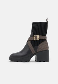 Černé ankle boots s masivním podpatkem, s pleteným svrškem, hnědým vzorovaným páskem a zlatými detaily s přezkou. Hladký kožený povrch.