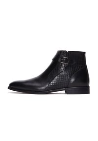 Botines negros con piel suave, un diseño de rejilla texturizada en el costado, una correa con hebilla y un tacón bajo apilado.