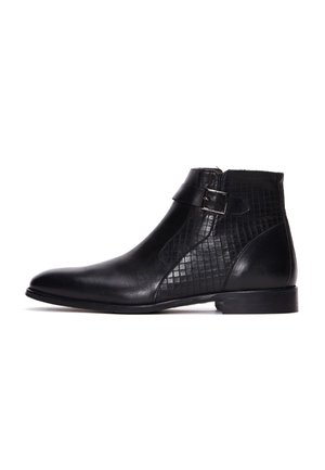 Botines negros con piel suave, un diseño de rejilla texturizada en el costado, una correa con hebilla y un tacón bajo apilado.